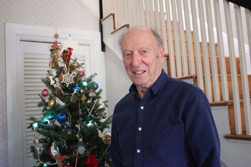 Morton Lebow, M.A. '49, posing near Christmas tree