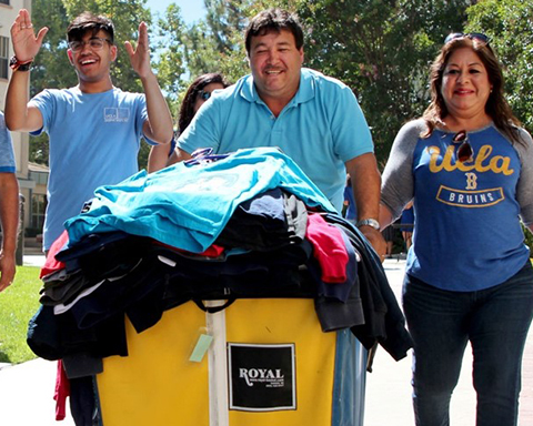 A Bruin family during move-in pushing a cart full of their student's personal belongings.