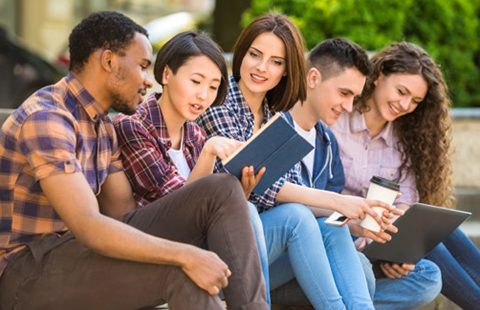 Five students studying on the steps outside of a building