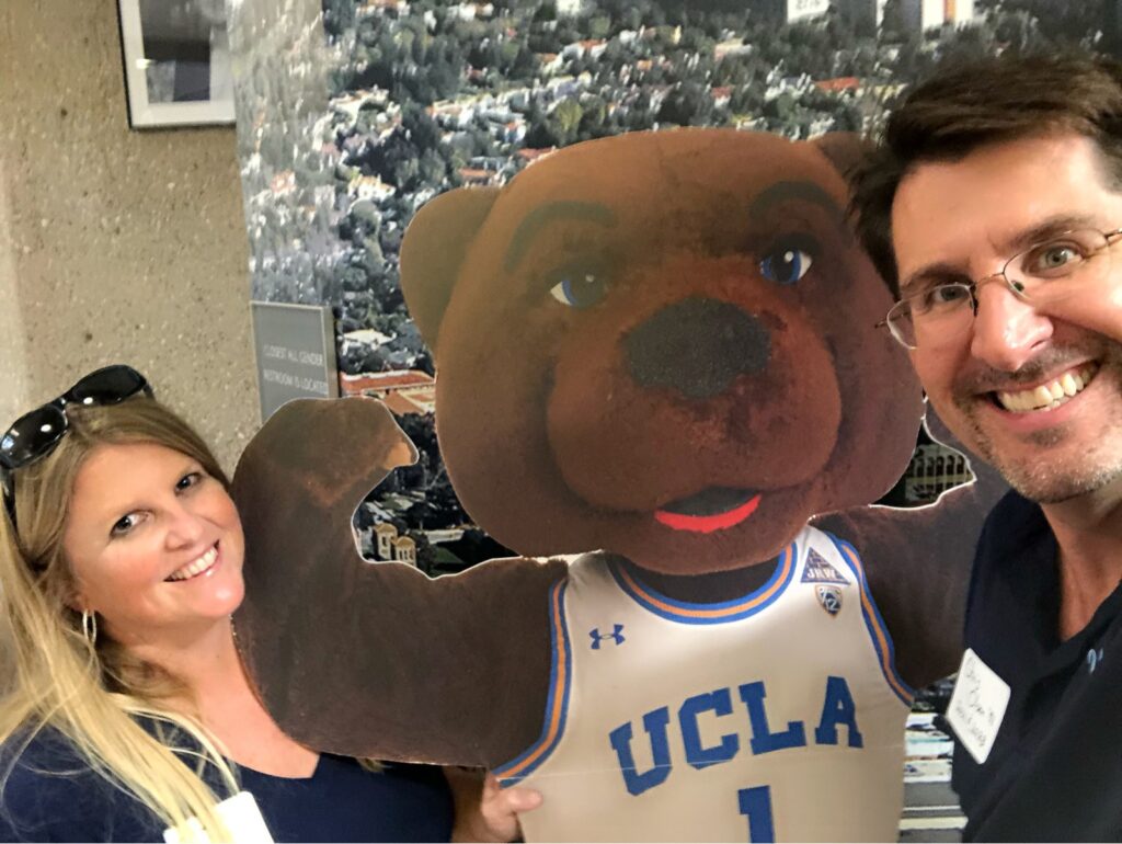 Annalise and Chris Olsen pose for a photo with a cardboard cut out of UCLA's mascot, Joe Bruin, between them.